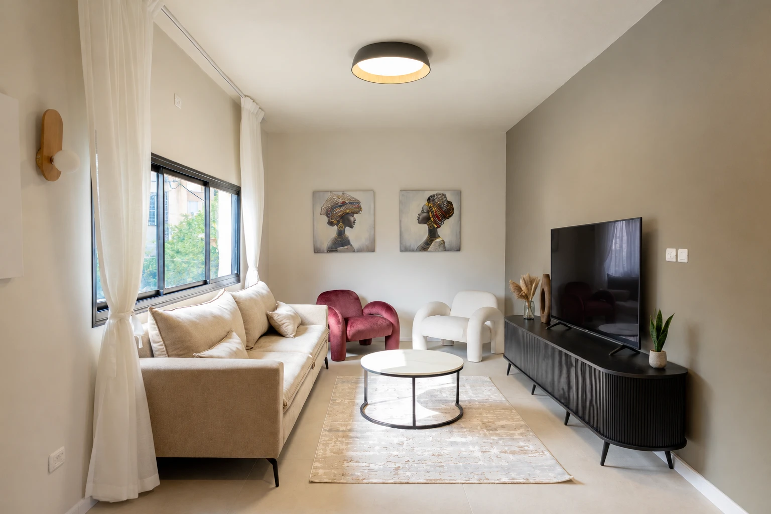 הסלון של Luxury Point: ספה בז׳, כורסת קטיפה בורדו, כורסת בוקלה לבנה, שולחן שיש עגול ושני ציורי דיוקן על הקיר