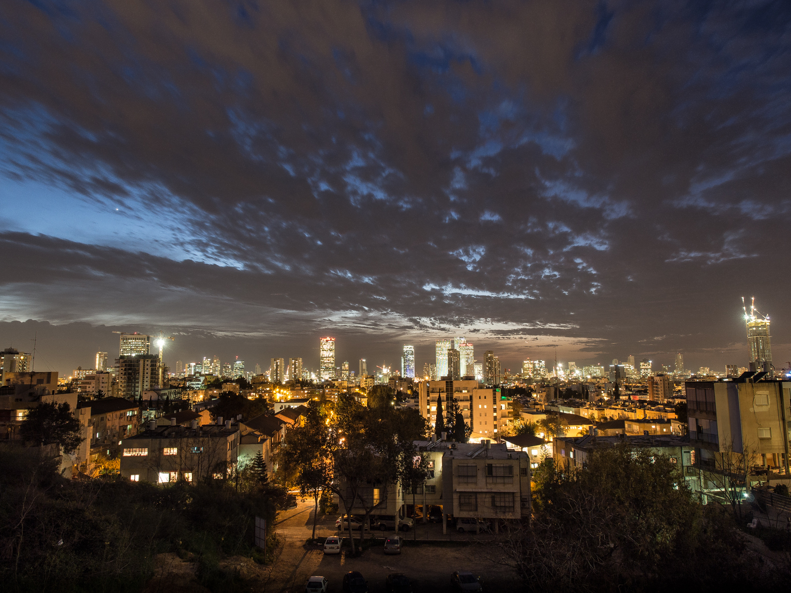 קו הרקיע של תל אביב בערב, אורות העיר מתחת לשמיים מעוננים, מבט מהגבעה בגבעתיים